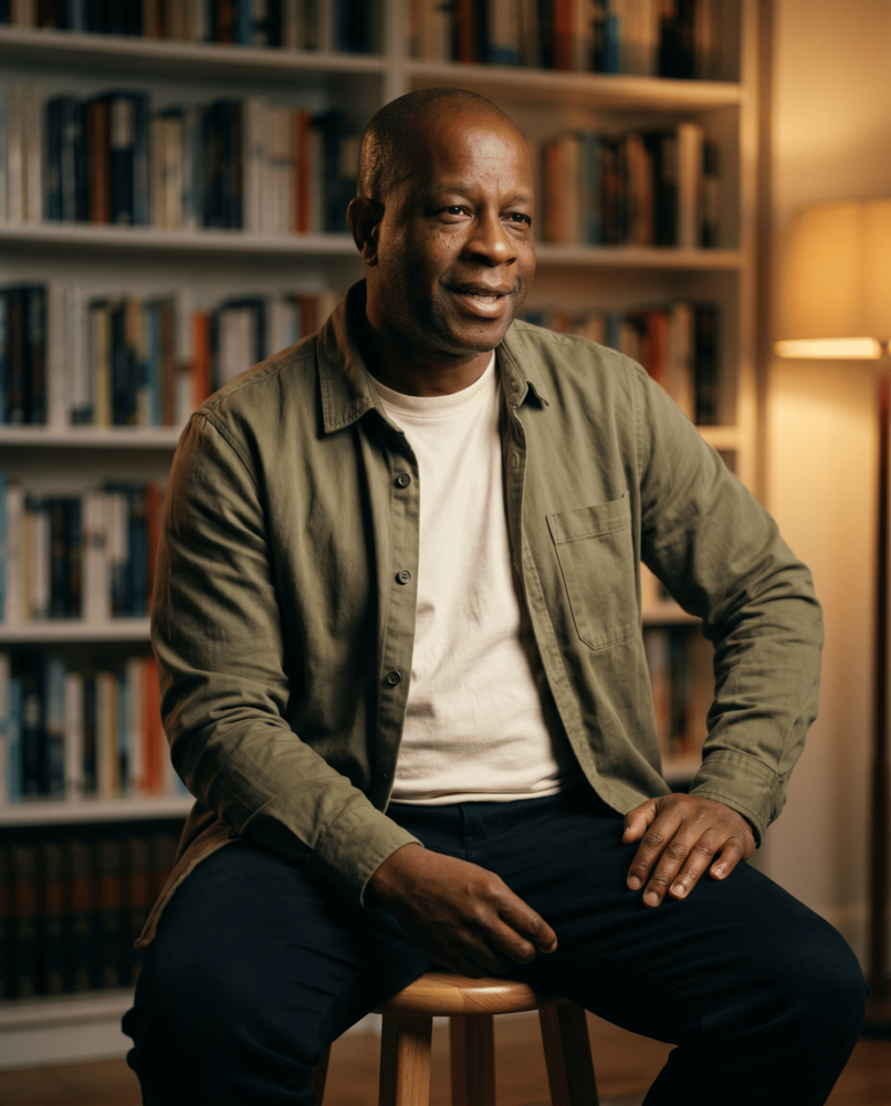 Tino, founder of Damask, seated in front of a bookshelf